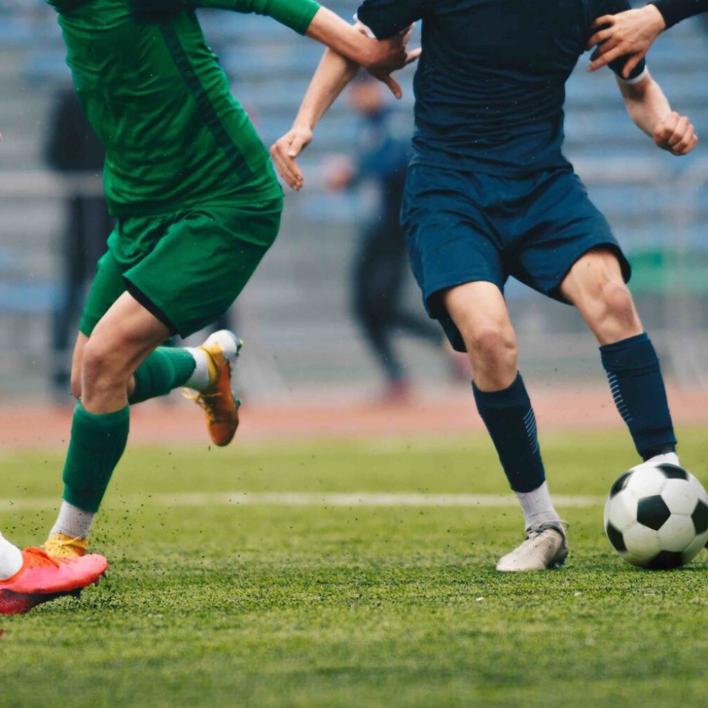 Footballers in action on the tournament game. Soccer football players competing for ball and kick ball during match in the stadium. Adult football competition