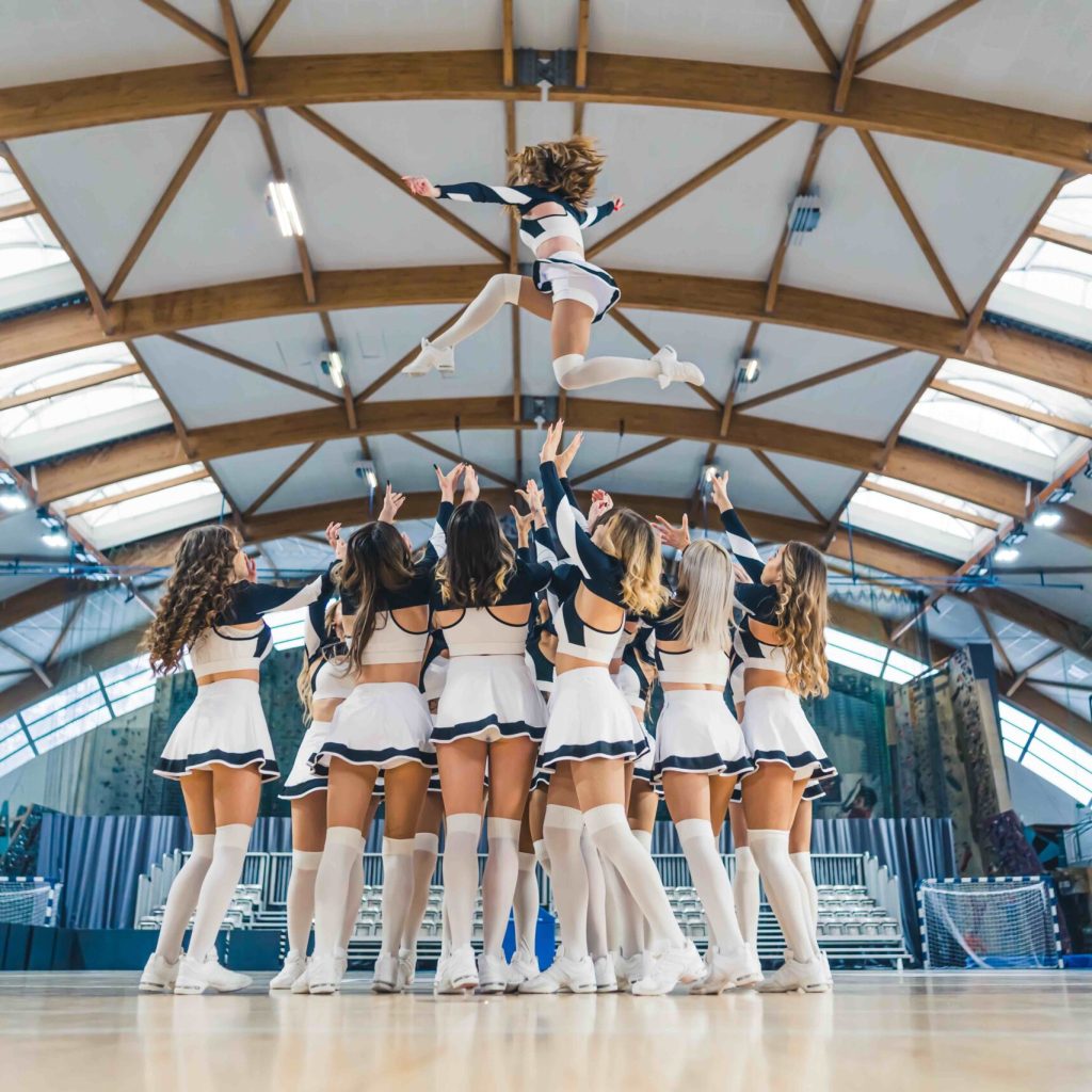 Full shot of a cheerleading squad hrowin one of their teammates high up in the air. Sport concept. High quality photo