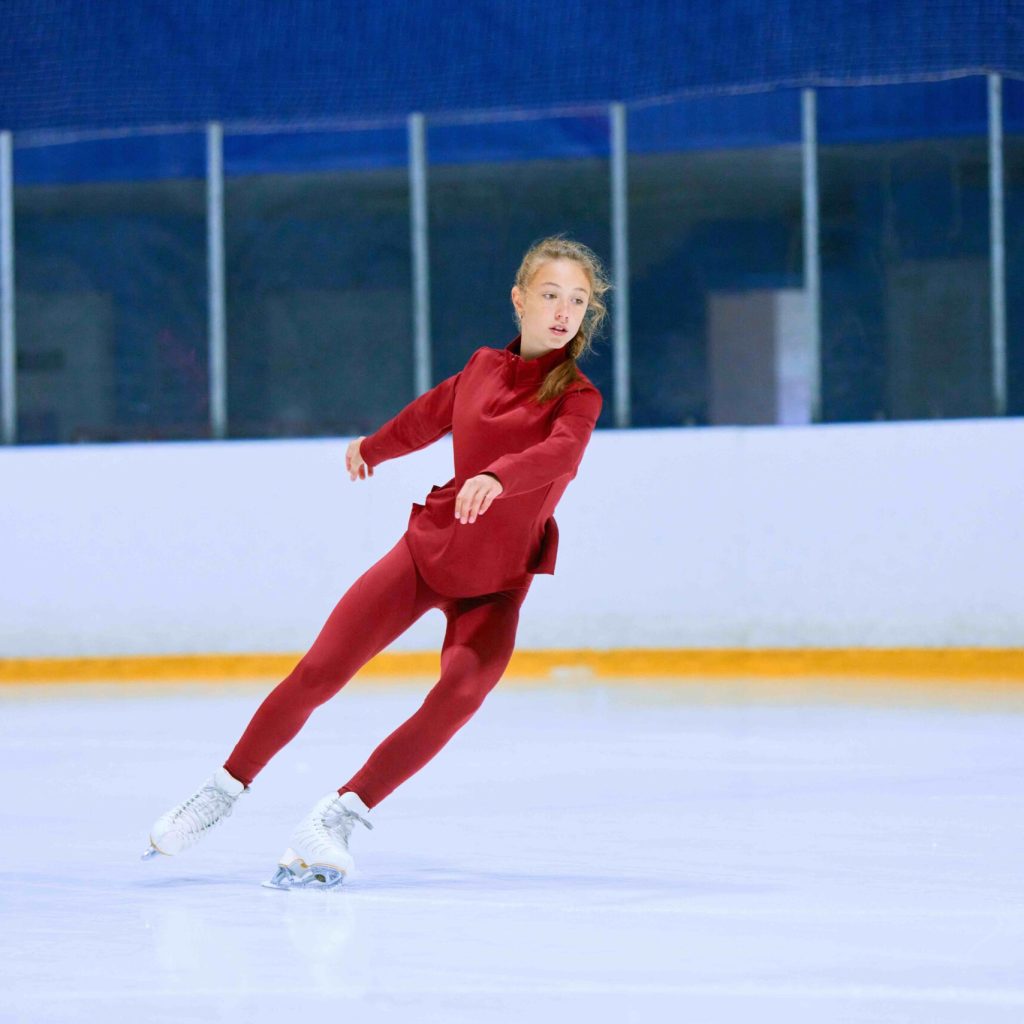 Concentrated and motivated teen girl in red sportswear training, skating on ice rink arena. Figure skating athlete. Concept of professional sport, competition, sport school, health, hobby, ad