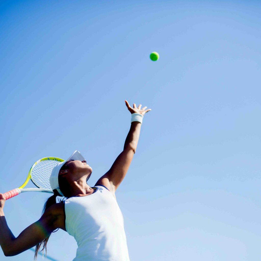 Beautiful female tennis player serving outdoor